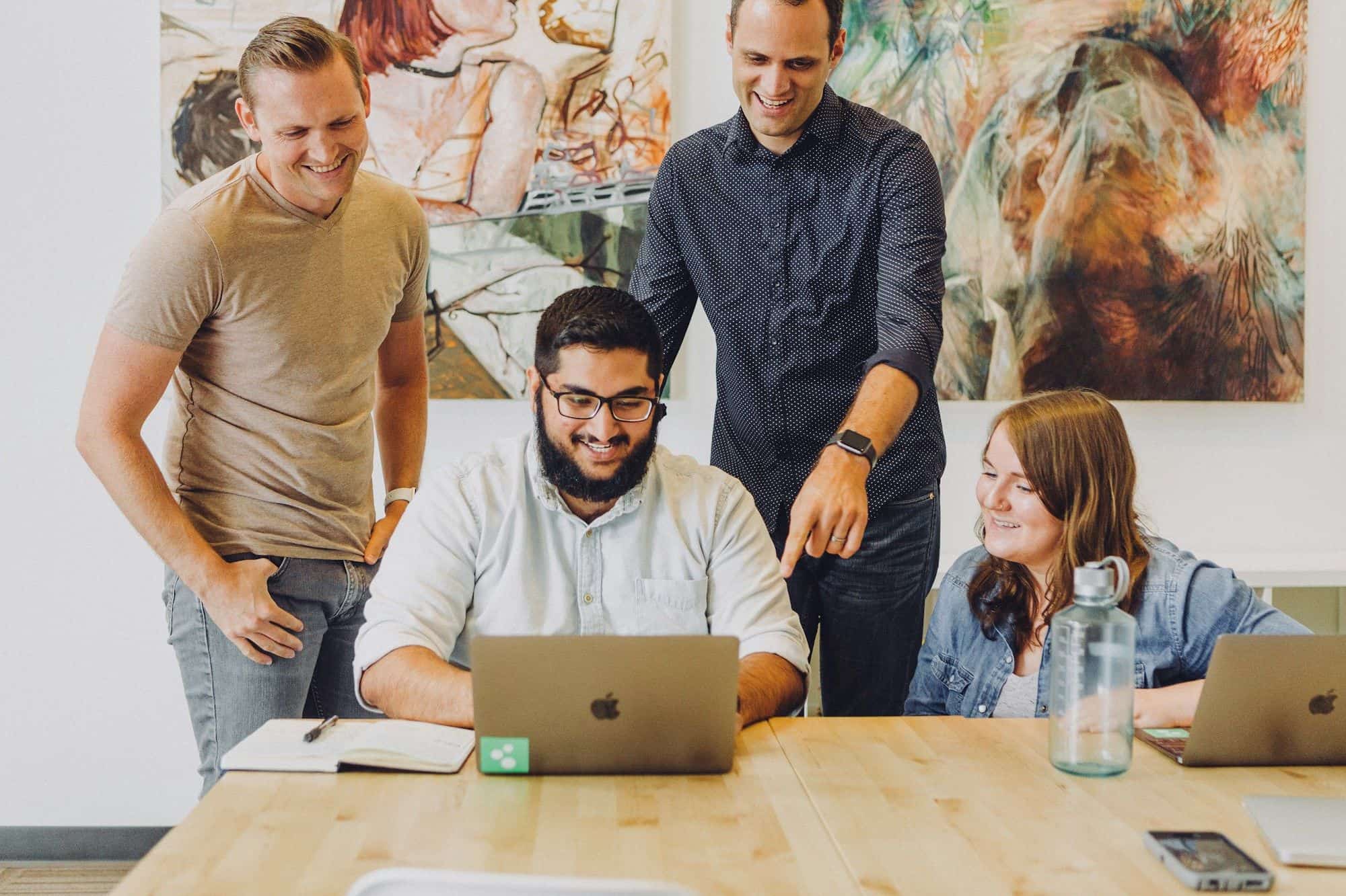 Colleagues gathered around a laptop, smiling