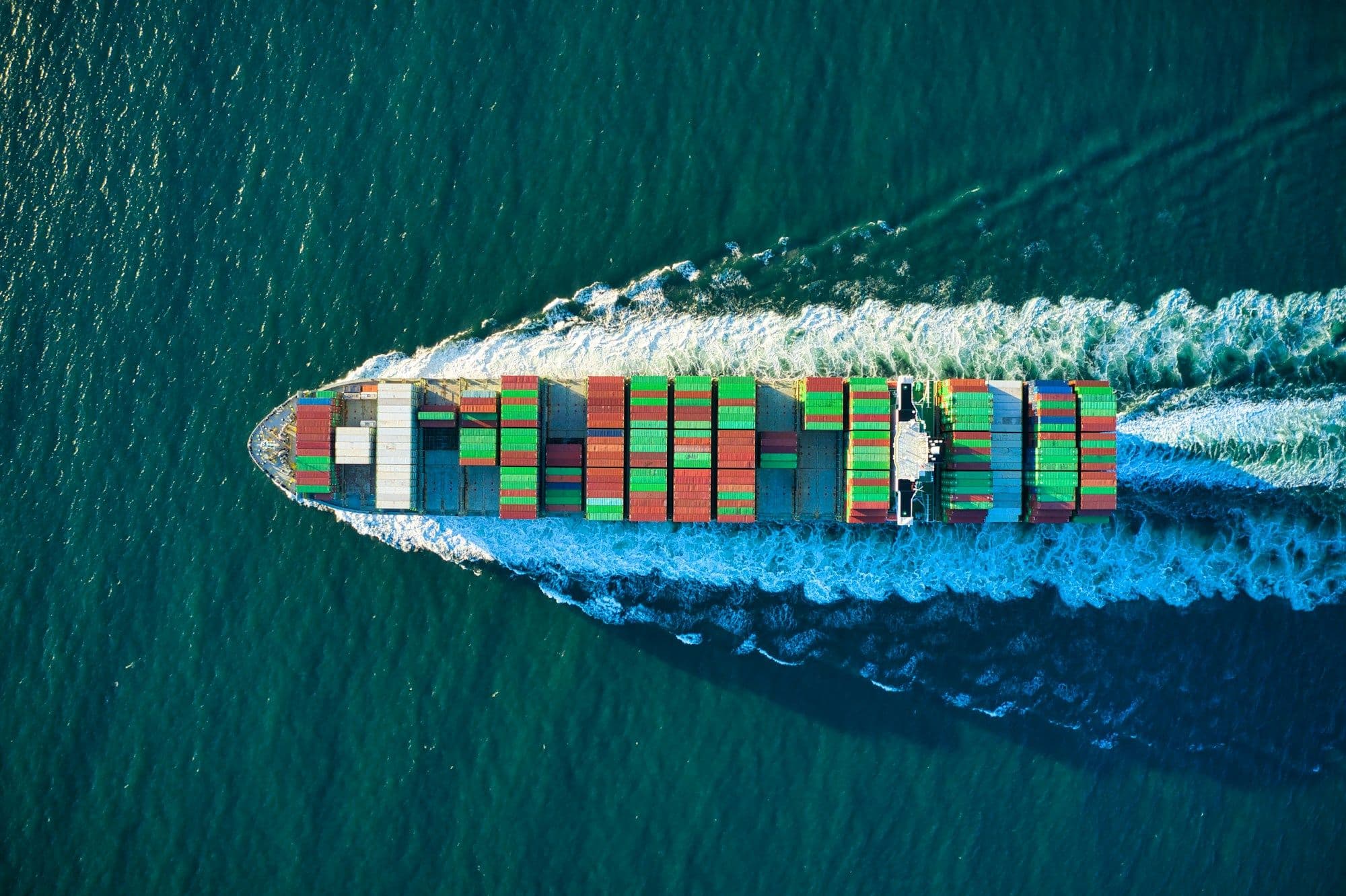Aerial view of a container ship cutting through deep blue water