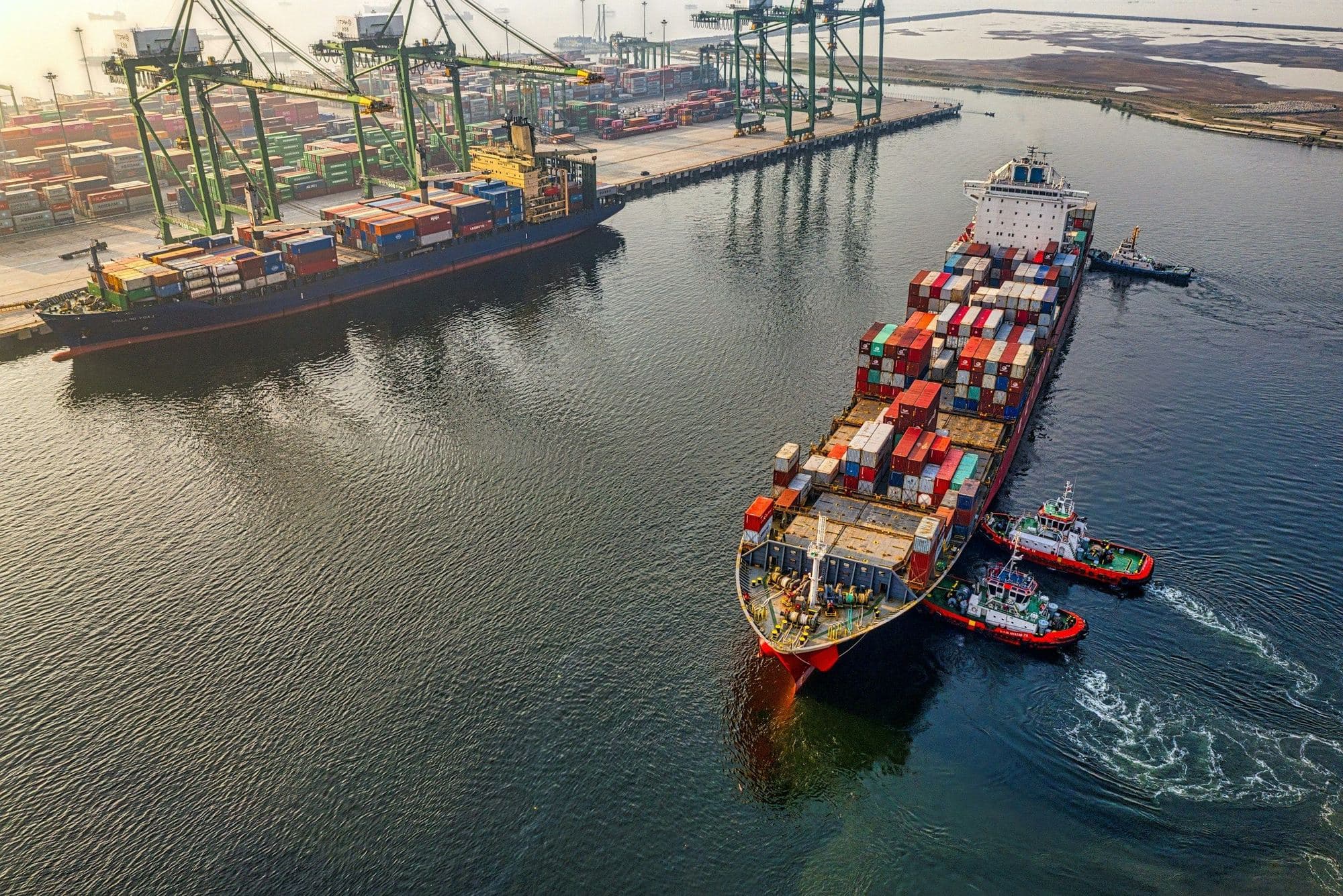Container ship guided by tugboats into a port at dawn